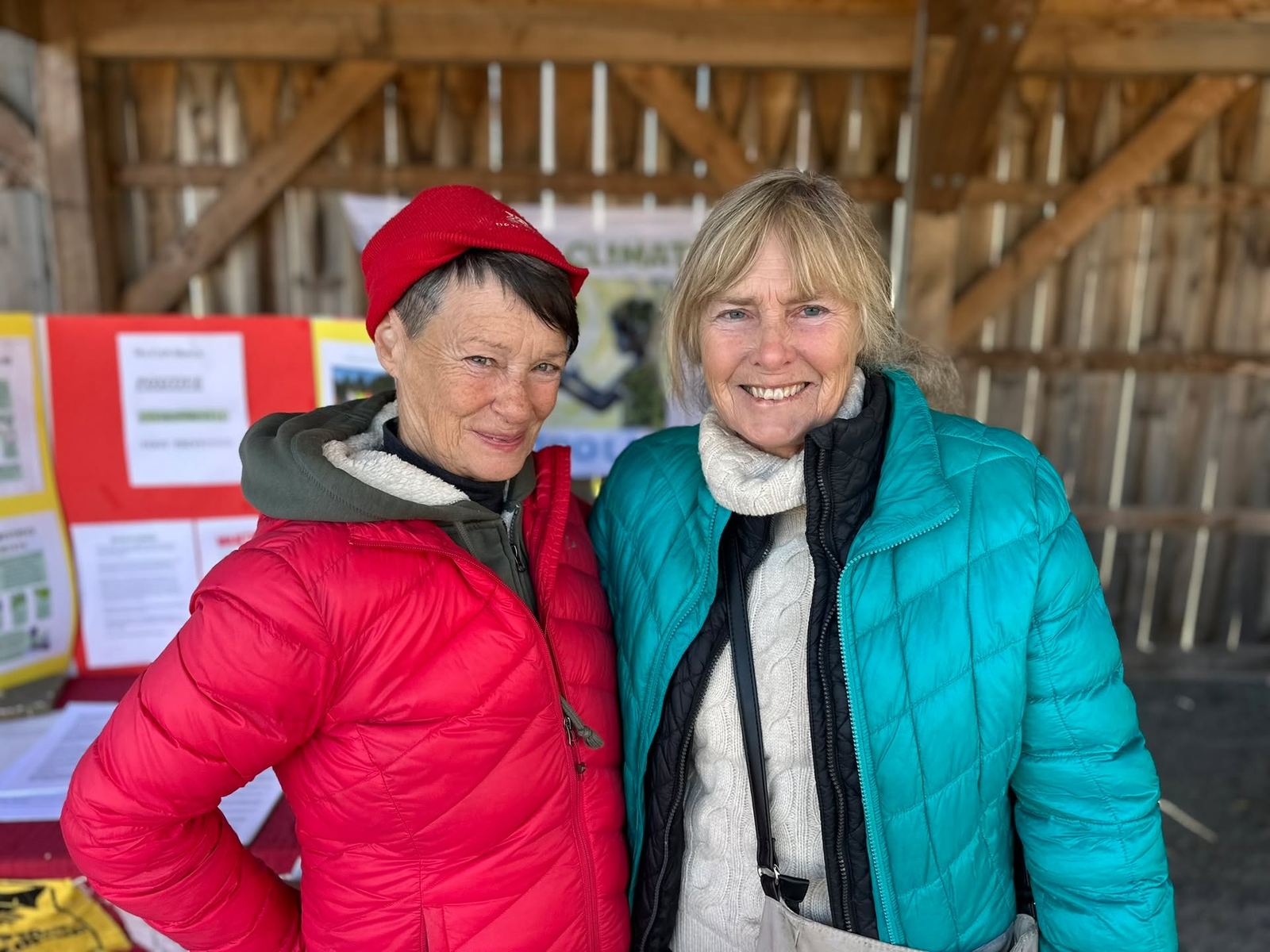 Deux femmes âgées en manteau d’hiver sourient dans un marché fermier.
